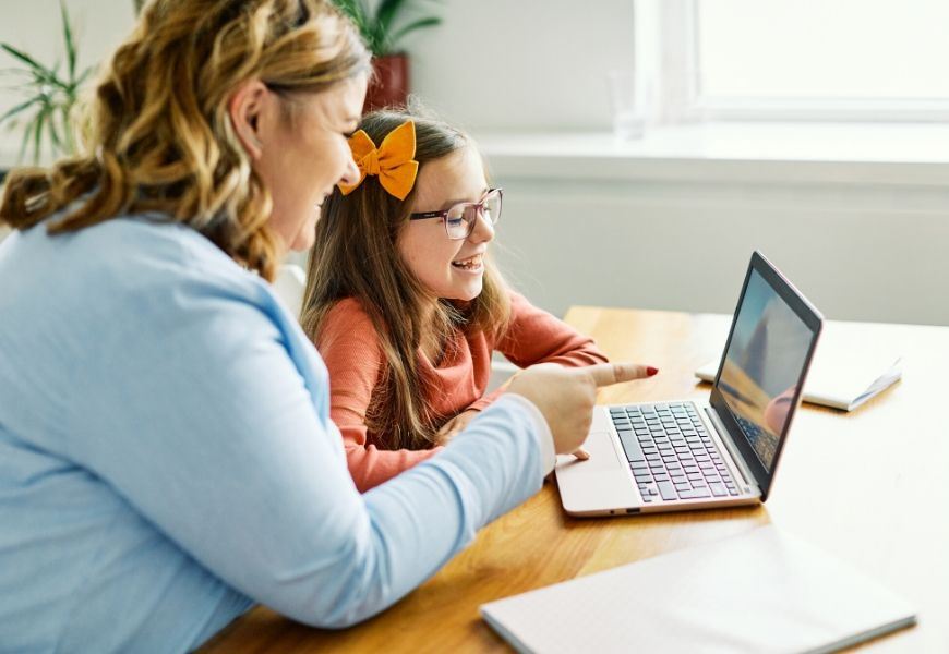 parent helping girl on laptop